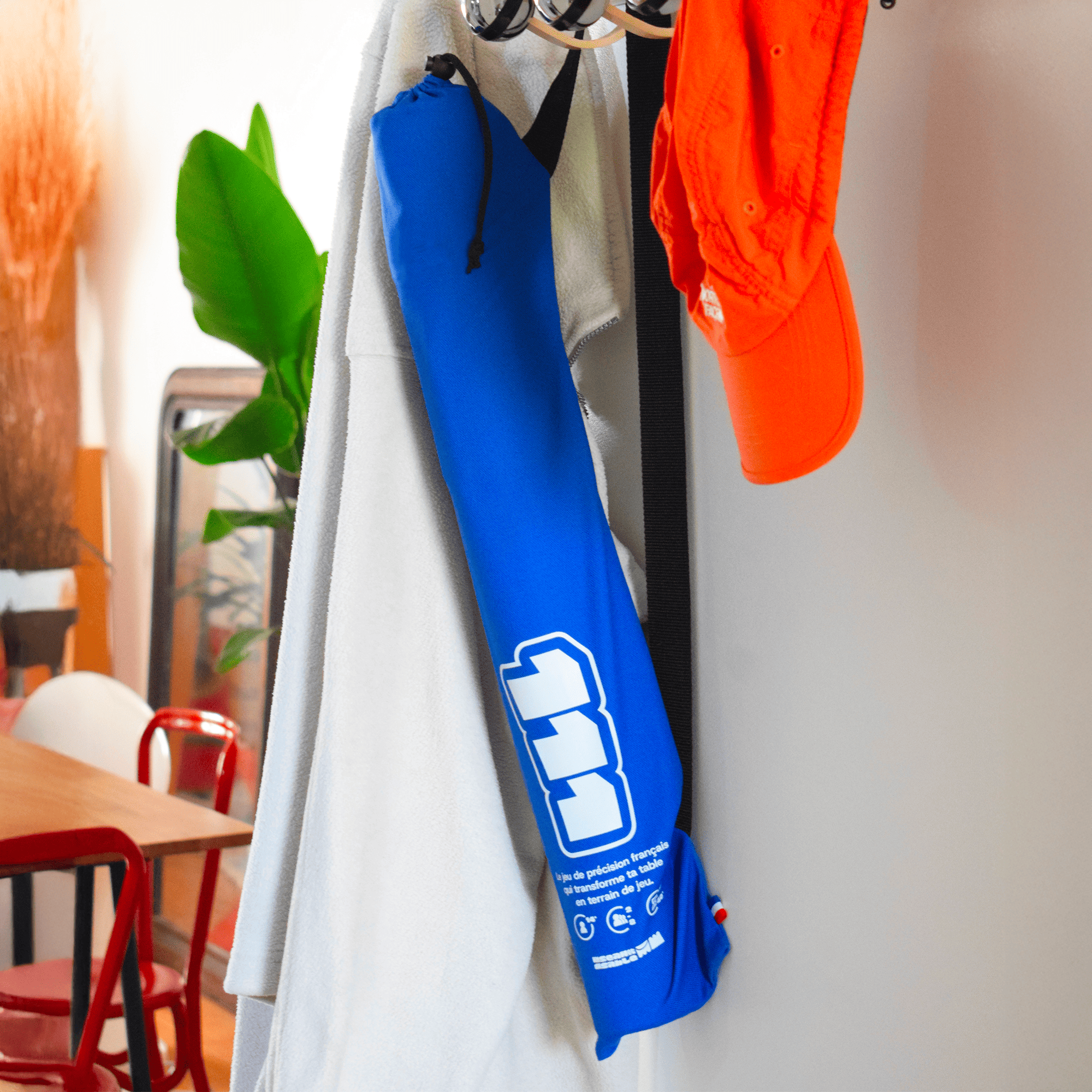 La sacoche du jeu 111 posé sur un porte manteau dans un appartement.