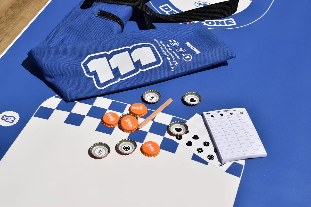 Kit 111 avec la sacoche, le plateau de jeu, le carnet de point, les stickers d'équipes, le dépliant des règles, un crayon, et les capsules 111, le 111, 111 le jeu, un seau et du sable, seau sable, us&ds